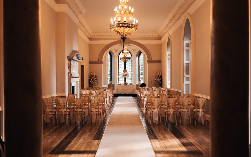 A ceremony room at Clearwell Castle set with chairs, an aisle and chandeliers