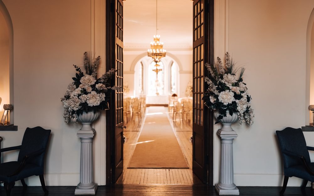 White floral arrangements framing the entrance to the ceremony room