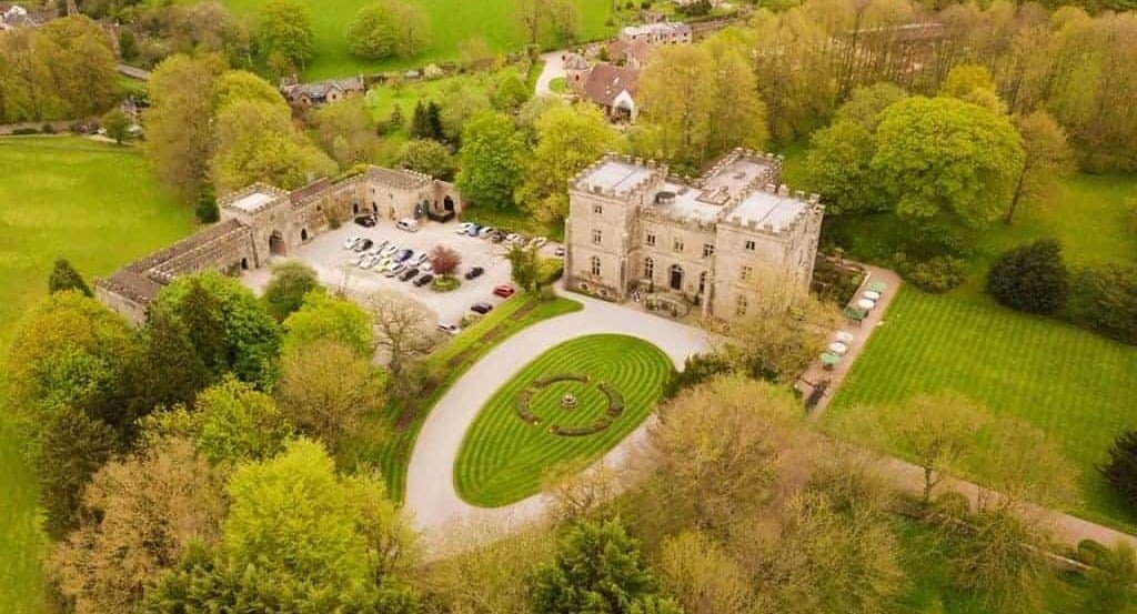 An aerial view of a country house showing its lawns, gravel parking and surrounding grounds