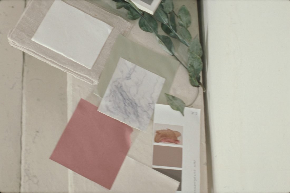 Fabric and paint samples laid out overlapping on a limewashed table