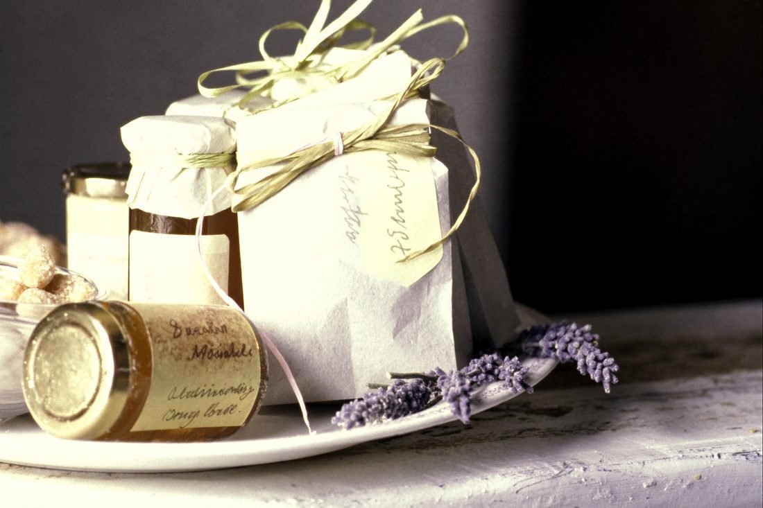 A tray of favours: kraft paper bags tied with twine and jars of honey with handwritten labels