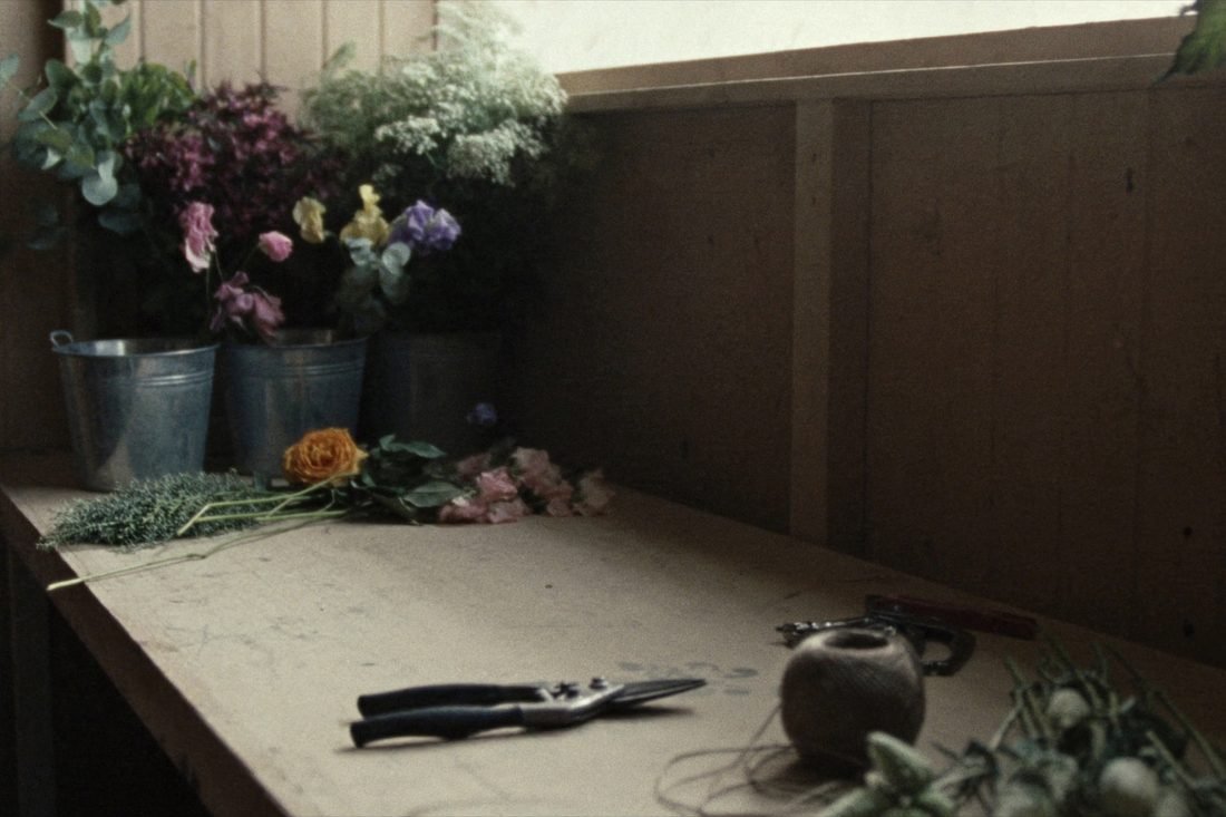 A potting shed bench with galvanised buckets of garden roses, sweet peas and eucalyptus