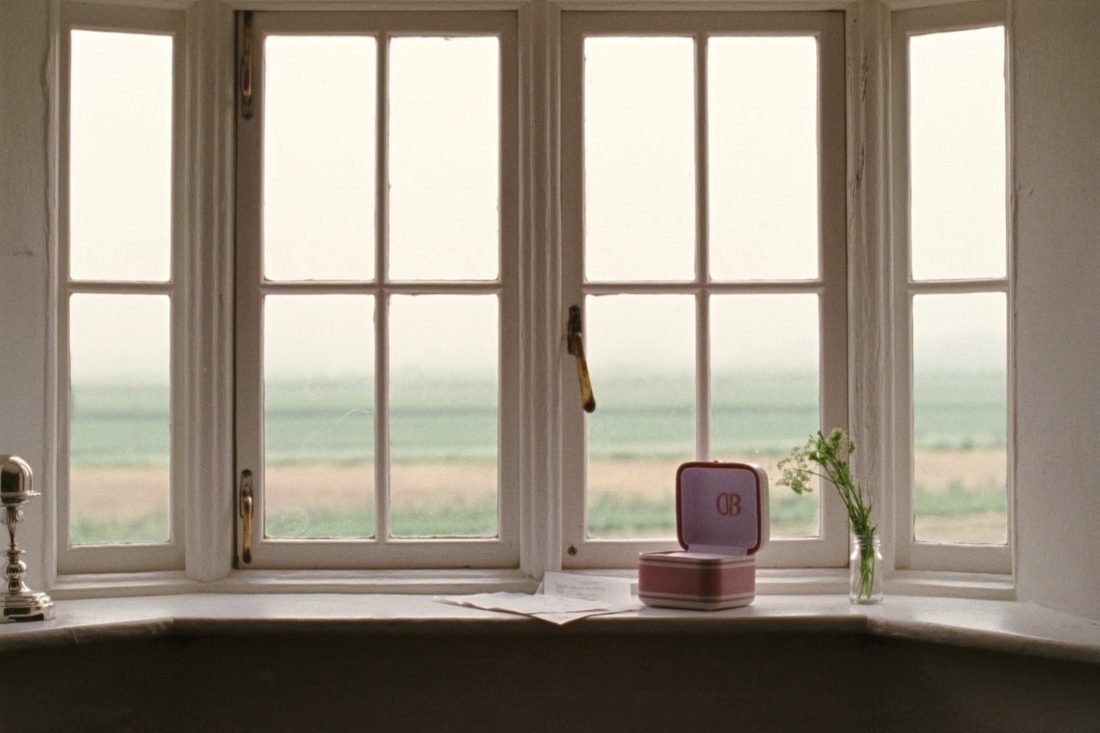 An open ring box on a deep painted windowsill with cow parsley in a small glass jar